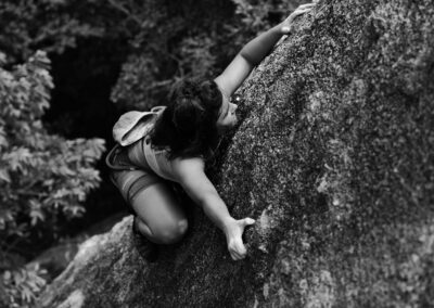 A determined woman climbing a rock face, showcasing strength and adventure in nature.
