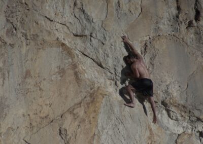 A male climber skillfully scales a challenging rock face outdoors, displaying strength and precision.